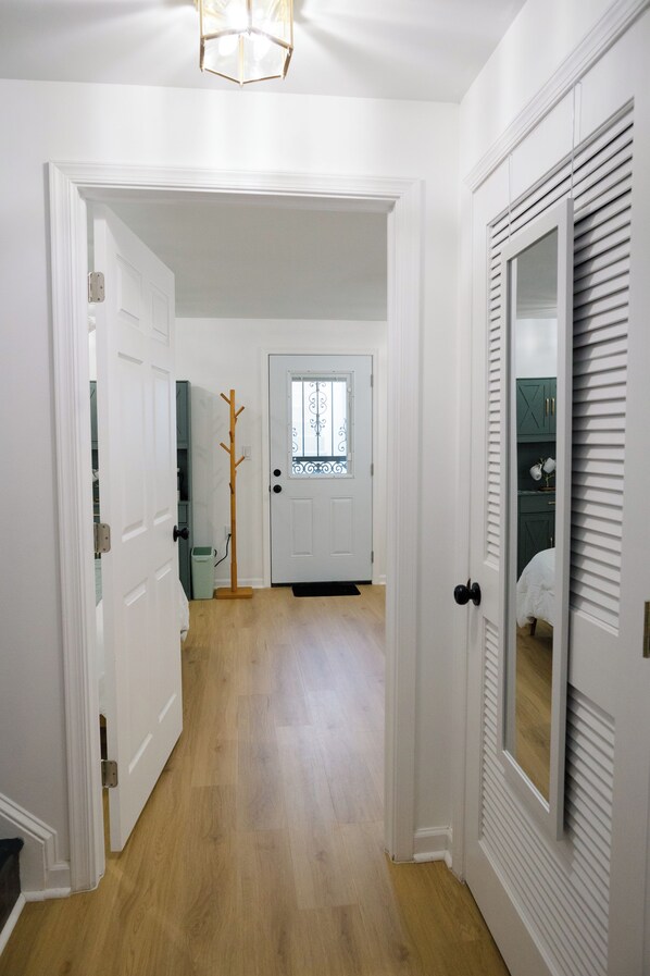 A hallway with white doors, a wooden floor, and a door with a window.