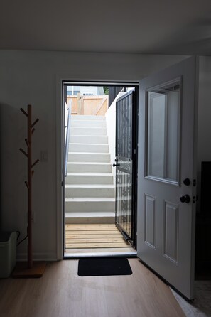 A staircase leading to an upper floor, a coat rack, and a door with a glass panel.