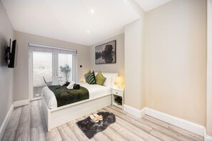 A modern bedroom with a bed, bedside table, and a window. - Comfy & Spacious|2 Bedroom Apartment|Seconds from Hammersmith Central Station (London)