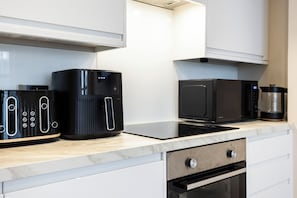 A modern kitchen with a coffee maker, microwave, and a built-in oven. - Comfy & Spacious|2 Bedroom Apartment|Seconds from Hammersmith Central Station (London)
