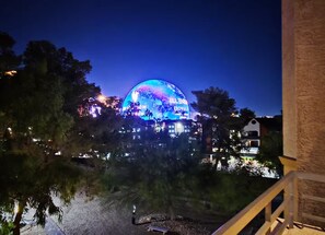 A dome-shaped building with illuminated signage, surrounded by trees and a railing. - Luxury Las Vegas Strip!  2BR Condo ~ Sphere view ~ 24/7 Pool 3-24 (Las Vegas)