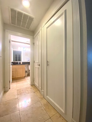 A hallway with a closed door, a window with blinds, and a view into a kitchen area. - Luxury Las Vegas Strip!  2BR Condo ~ Sphere view ~ 24/7 Pool 3-24 (Las Vegas)