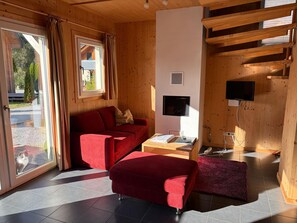 A room with a red sofa, a small table, a TV, and a window with curtains. - 012 Mw21b in Murau (Murau)