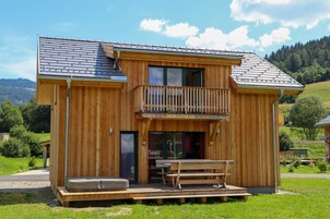 Una cabaña de madera con balcón, un patio y vistas del paisaje circundante.