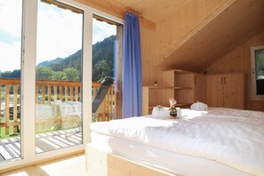 A wooden cabin bedroom with a bed, a small cabinet, and a view of a balcony. - 002 MW5 in Murau (Murau)