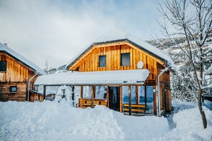 A wooden cabin with a covered porch and a bench, surrounded by snow. - 026 W6 in St Georgen am Kreischberg (Sankt Georgen am Kreischberg)