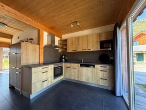 A modern kitchen with wooden cabinets, a black countertop, and a large window. - 014 Mw23 in Murau (Murau)