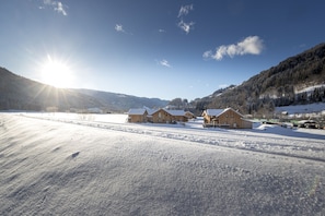 Schneebedeckte Landschaft mit Holzbauten und blauem Himmel.