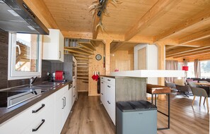 Eine moderne Küche mit Holzschränken, einem eingebauten Backofen und einem Essbereich mit Tisch und Stühlen.