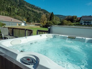 A hot tub with a control panel, surrounded by a wooden deck and a view of a mountainous landscape. - 001 MW1 in Murau (Murau)