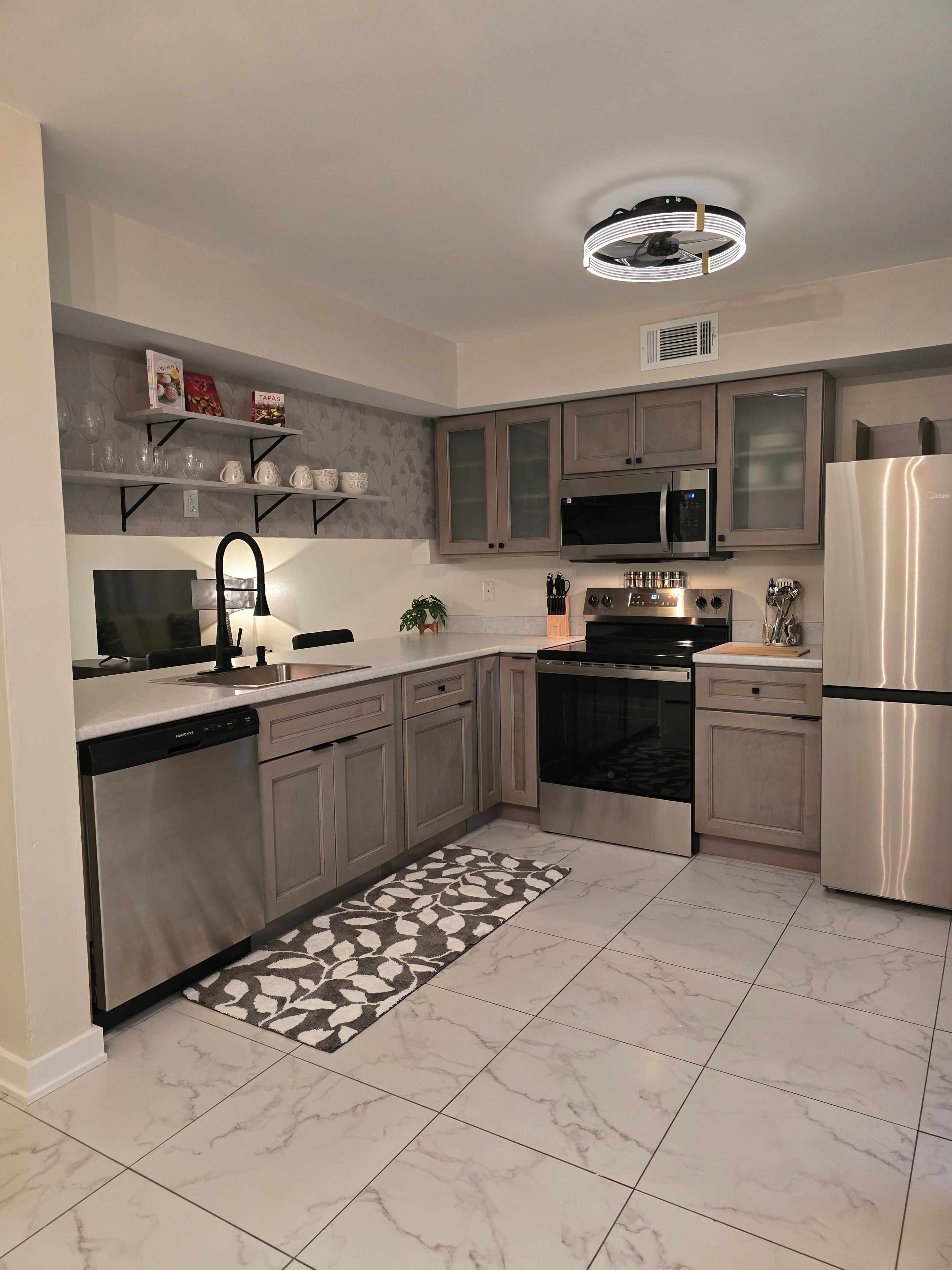 Una cucina moderna con elettrodomestici in acciaio inossidabile, lavastoviglie e un tappeto decorato.