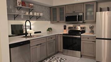 Una cucina moderna con elettrodomestici in acciaio inossidabile, lavastoviglie e un tappeto decorato.