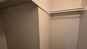 A corner of a room with a dark wooden floor, white walls, and a white closet with a door partially open.
