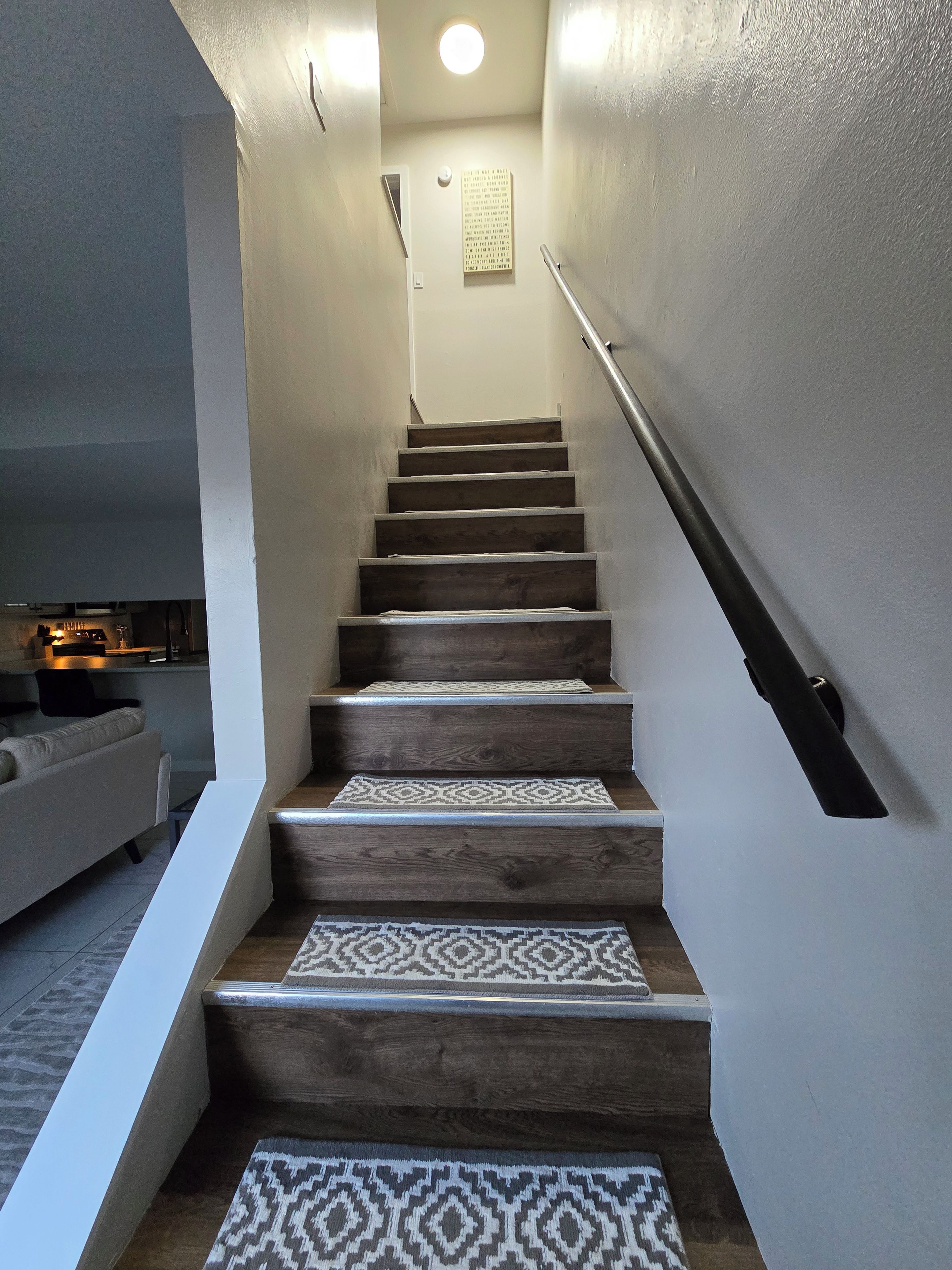 Una scala con gradini in legno e tappeti decorati, che porta a una piattaforma illuminata.