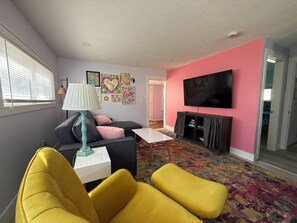 Una sala de estar con un sofá, un sillón amarillo, un televisor y una lámpara.