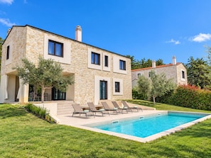Ein zweigeschossiges Steinhaus mit Swimmingpool, Außenbereich und einem gepflegten Garten.