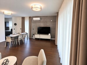 Ein modernes Wohnzimmer mit Essbereich, Flachbildfernseher und integrierter Klimaanlage.