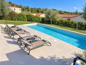 Ein Schwimmbecken mit Liegestühlen und einer gefliesten Poolterrasse.