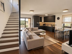 Ein modernes Interieur mit Treppe, einer Sofagruppe, einem Essbereich und einer Küche.