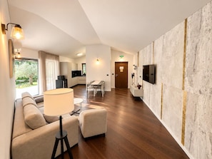 Een moderne hotelkamer met een bank, een lamp, een eettafel en een aan de muur bevestigde televisie.