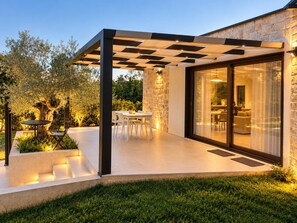 Eine moderne Außenpatio mit Pergola, Essbereich und einer Steinmauer.