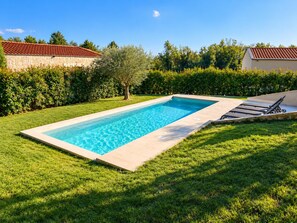 A rectangular swimming pool with a clear blue water surface, surrounded by a well-maintained lawn and a hedge. - Villa Casa Veritas - Four Bedroom Villa, Sleeps 8 (Sveti Ivan)