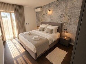 A modern bedroom with a large bed, two bedside lamps, a wall-mounted air conditioner, and a patterned wallpaper. - Villa Casa Veritas - Four Bedroom Villa, Sleeps 8 (Sveti Ivan)