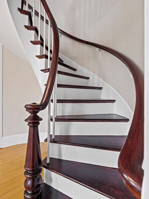 A wooden staircase with a curved design and a handrail.
