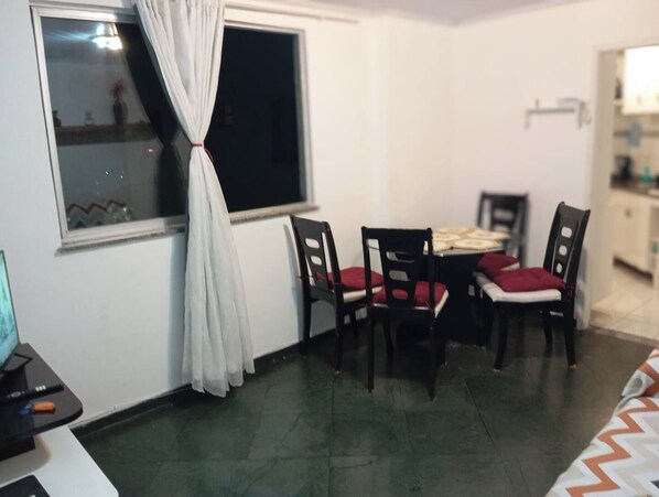 A dining area with a table and chairs, a window with curtains, and a view of the outside.