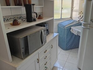 A compact kitchen with a microwave, coffee maker, and a water heater.