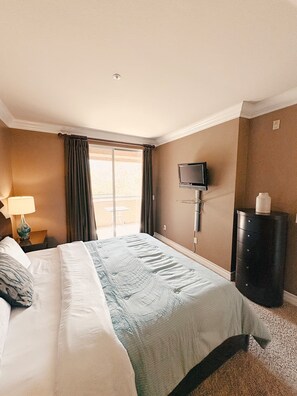 Ein Hotelzimmer mit einem Bett, einem an der Wand montierten Fernseher, einem Heizgerät und einem Fenster mit Vorhängen.