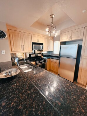 A kitchen with granite countertops, stainless steel appliances, wooden cabinets, and a built-in microwave. - Luxury Las Vegas Strip!  1BR Private Residences Penthouse Condo ~ 24/7 Pool 2-42 (Las Vegas)