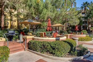 An outdoor patio area with seating, a barbecue grill, and umbrellas. - Luxury Las Vegas Strip!  1BR Private Residences Penthouse Condo ~ 24/7 Pool 2-42 (Las Vegas)