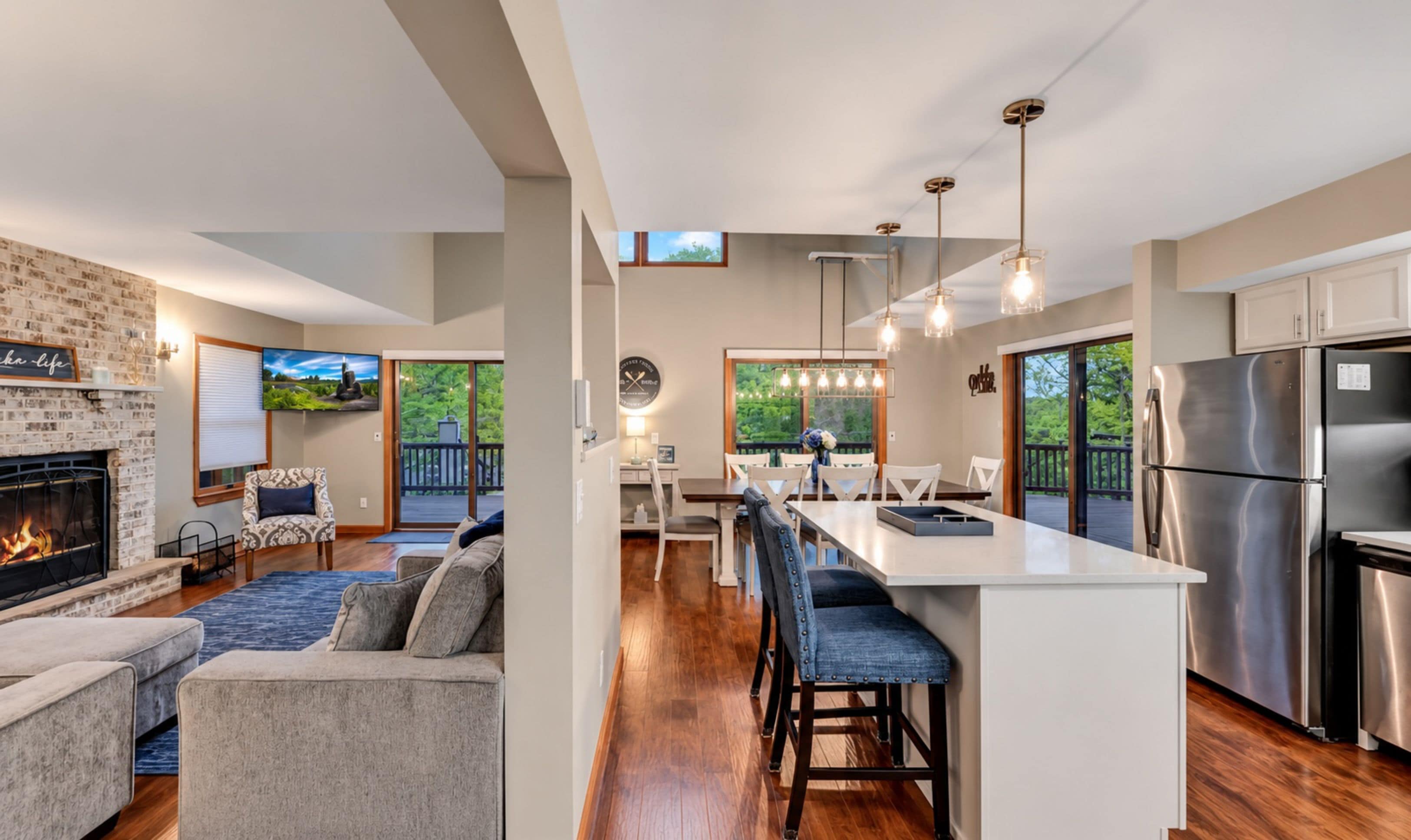 A modern kitchen with a central island, stainless steel appliances, and a dining area with a view of the outdoors.