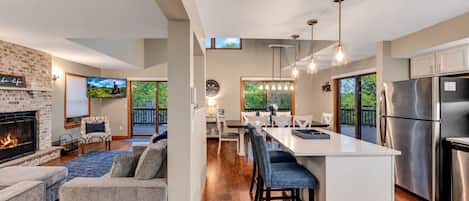 A modern kitchen with a central island, stainless steel appliances, and a dining area with a view of the outdoors.