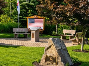 Ein Gedenkpark mit einer Flagge, Bänken und einer Gedenktafel.