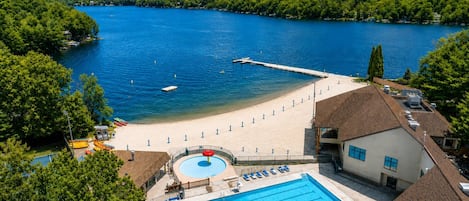 A resort with a swimming pool, beach area, and a view of a lake.