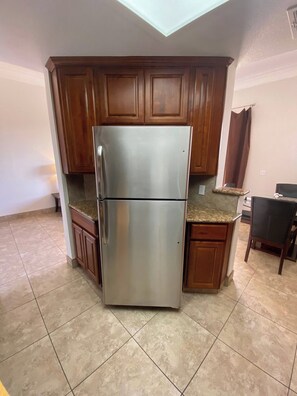 A kitchen with a stainless steel refrigerator, wooden cabinets, a granite countertop, and a skylight. - Luxury Las Vegas Strip!  1BR Private Residences Penthouse Condo ~ 24/7 Pool 7-40 (Las Vegas)