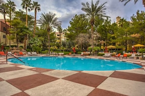 A swimming pool with lounge chairs and umbrellas, surrounded by palm trees and buildings. - Luxury Las Vegas Strip!  1BR Private Residences Penthouse Condo ~ 24/7 Pool 7-40 (Las Vegas)
