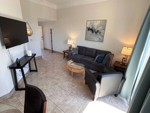 Uma sala de estar moderna com televisão de tela plana, sofá, mesa de centro e abajur.