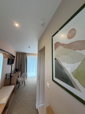A hotel room with a desk, chair, and a large abstract painting on the wall. - Logis Hôtel & Restaurant - L'Hôtantic (Maninghem)