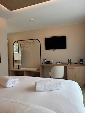 Une chambre d’hôtel équipée d’un lit, d’un bureau, d’une chaise, d’un téléviseur à écran plat et d’un miroir.