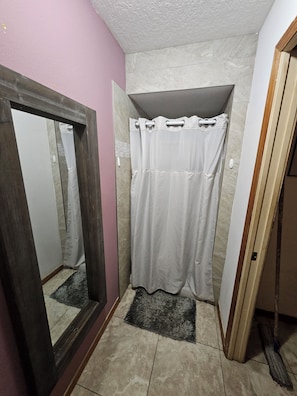 A bathroom with a shower, a mirror, and a tiled floor. - Cozy 1-bedroom in tranquil Kissimmee with private entrance (Kissimmee)