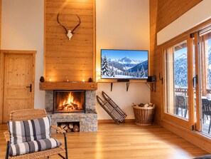 Ein gemütliches Wohnzimmer mit Kamin, einem an der Wand montierten Fernseher und einer Holztür.