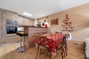 Una cocina moderna con armarios de madera, un refrigerador de acero inoxidable y un comedor con mantel rojo.