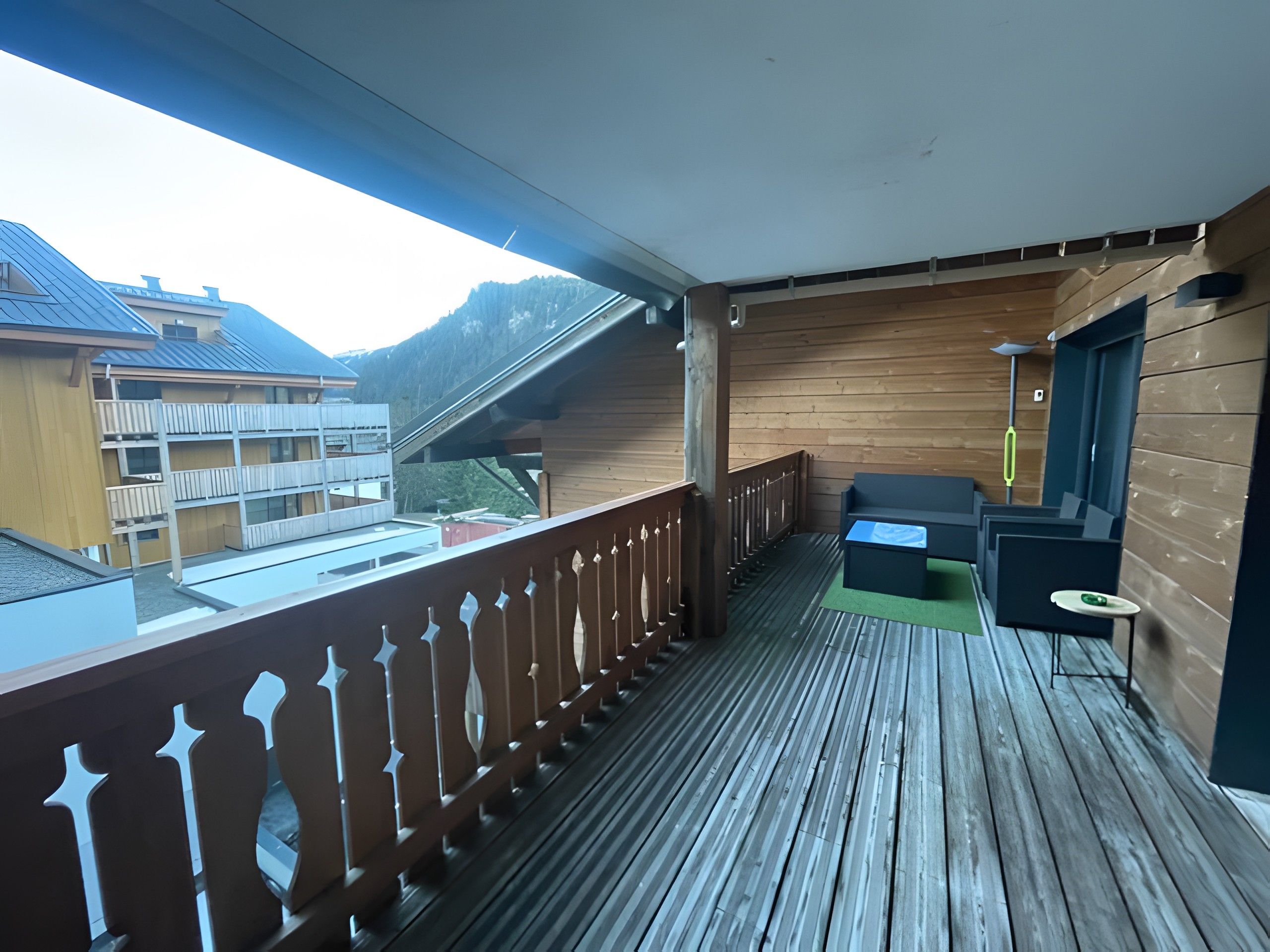 Un balcon en bois offrant une vue sur les bâtiments et les montagnes.