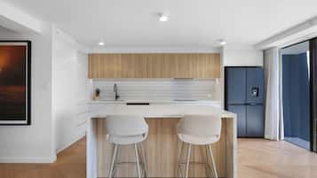 A modern kitchen with a wooden countertop, two bar stools, and a built-in refrigerator.