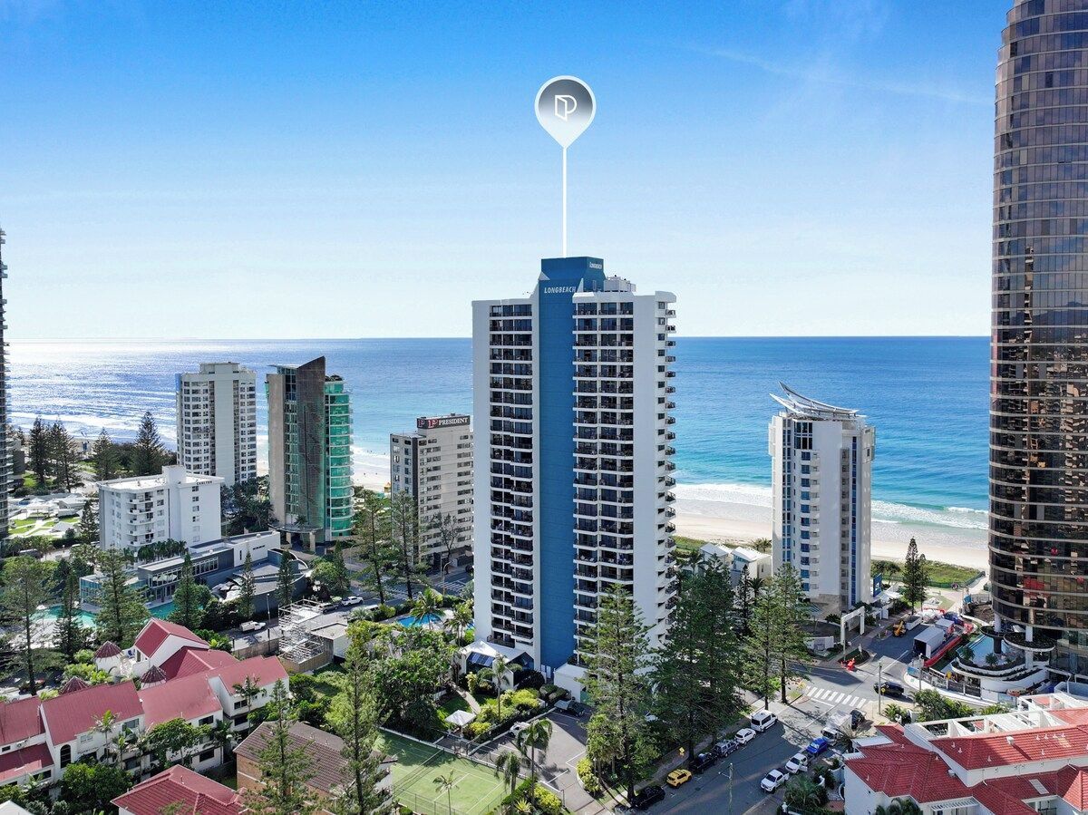 A high-rise hotel with a prominent 'Long Beach' sign, surrounded by other buildings and a beach.