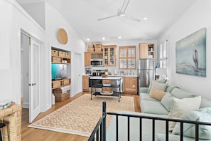 A modern kitchen with wooden cabinets, a dining table, and a refrigerator. - Palms by the Sea Carriage House | Community Pool | Pets Welcome (Seacrest Beach)