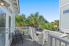 A balcony with a white railing, a bench, and palm trees. - Palms by the Sea Carriage House | Community Pool | Pets Welcome (Seacrest Beach)